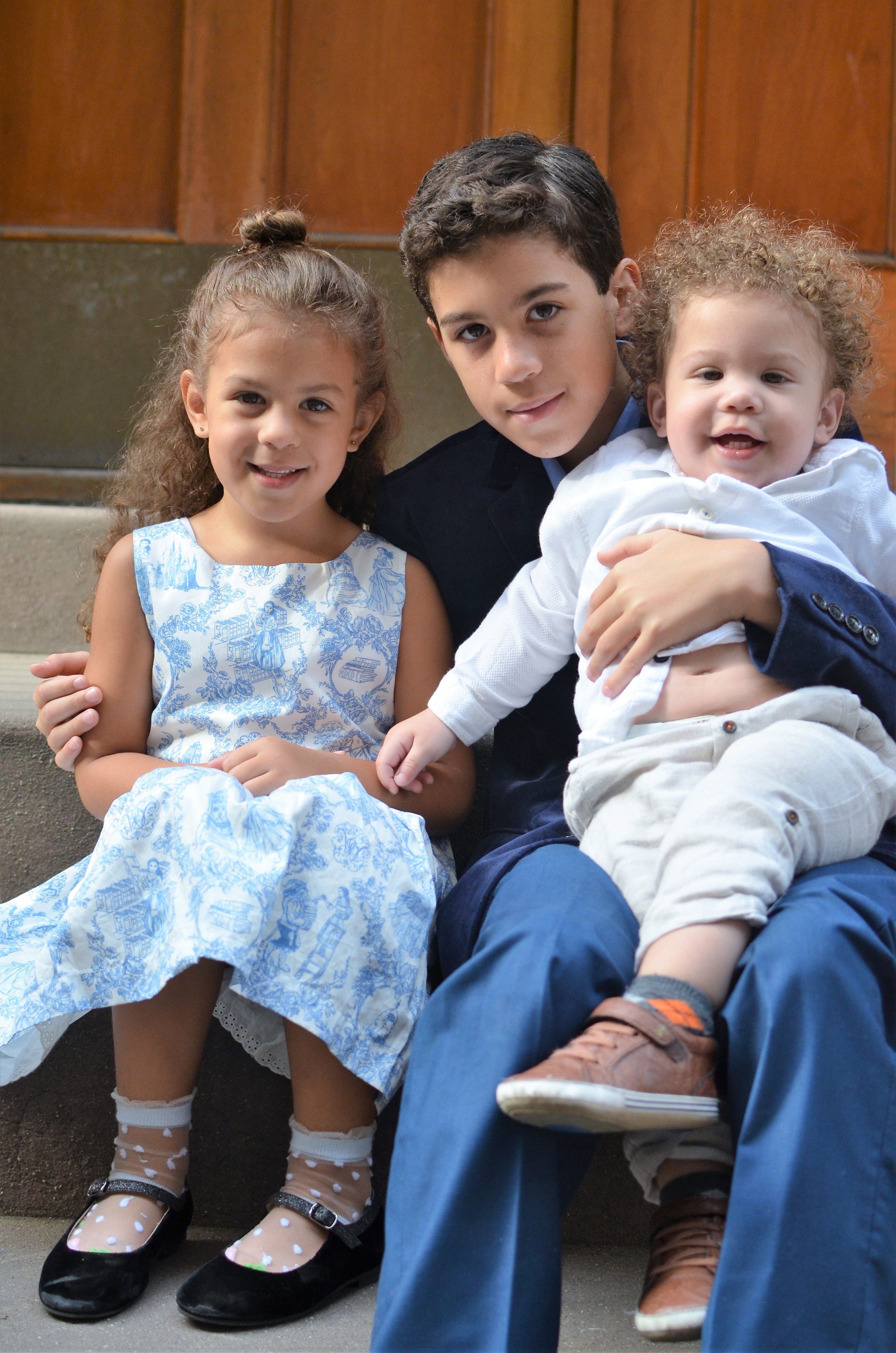 three elementary aged sibling sitting on stoop