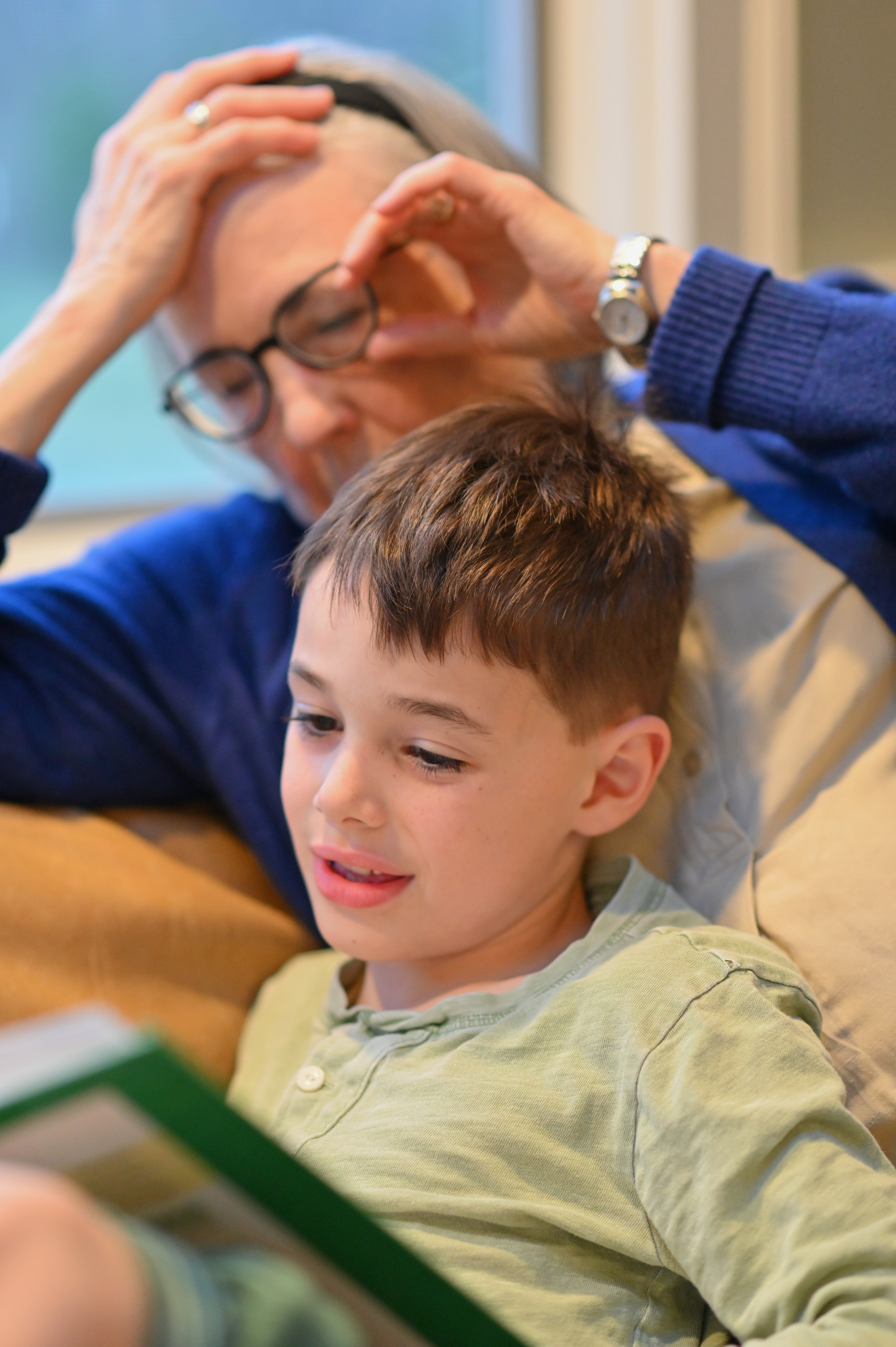 boy reading with grandma looking on