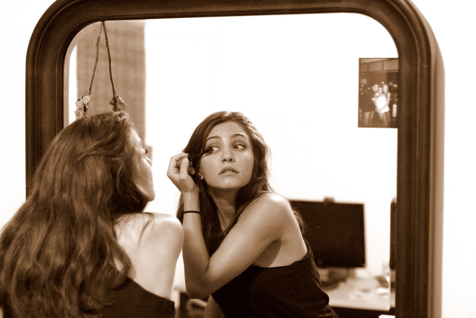 beautiful woman applying mascara in the mirror