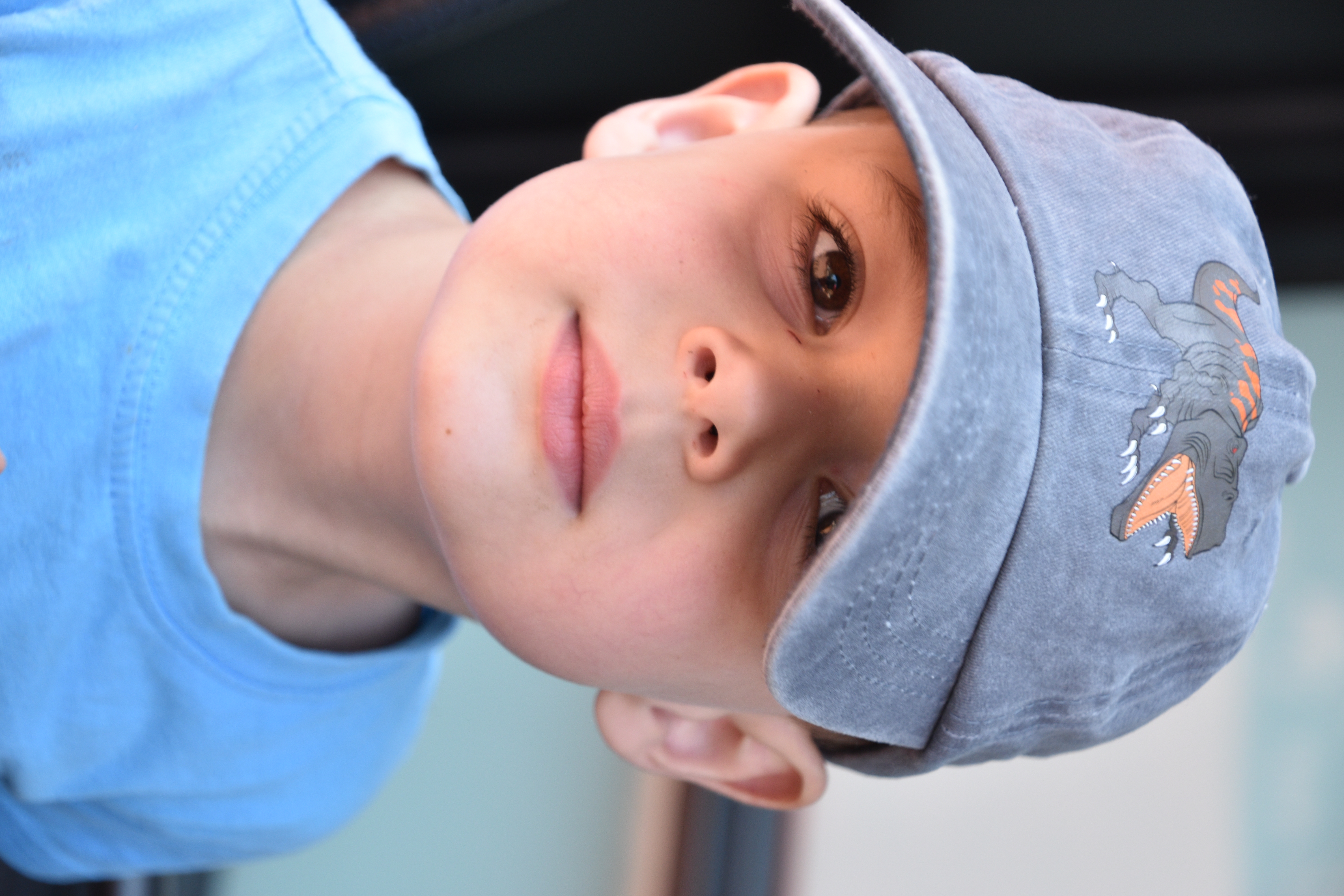 boy peering out from under baseball cap